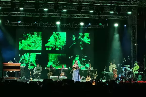 Foto de Silvana Estrada cantando en el escenario con una guitarra a un lado.