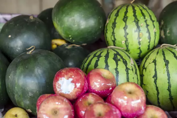 Watermelons and apples for sale at a public market.
