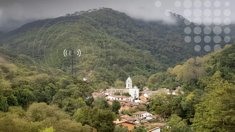 Un pueblito en medio de cerros con una antena de telecomunicaciones simulando dar señal de conectividad 