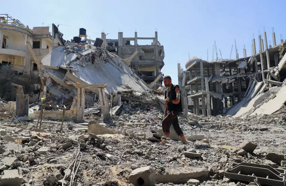 El hombre palestino Jehad Al-Shagnobi, que resultó herido en un ataque israelí anterior contra su casa, camina con un fijador externo en su brazo para inspeccionar los daños en su casa en el barrio de Sabra, después de una operación israelí, en el barrio de Sabra en la ciudad de Gaza, el 8 de octubre de 2025. (Imagen principal del artículo web 'Israel y Hamás alcanzan un acuerdo, pero queda todavía un gran pendiente').