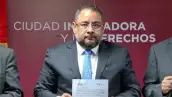 Omar Reyes Colmenares, titular de la Unidad de Inteligencia Financiera, sostiene un documento con ambas manos. 