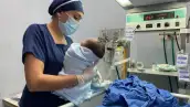 Personal médico sostiene y atiende a un recién nacido junto a equipo especializado en una unidad hospitalaria.