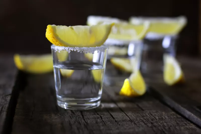 stack of tequila with salt and lemon on a wooden background