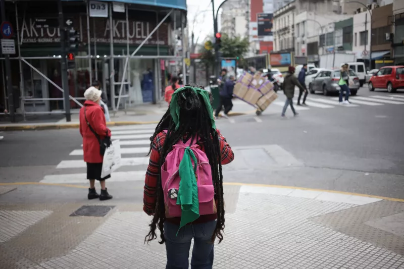 Persona no identificada caminando por la Avenida Corrientes con un pañuelo verde pro aborto en su mochila en Buenos Aires, Argentina