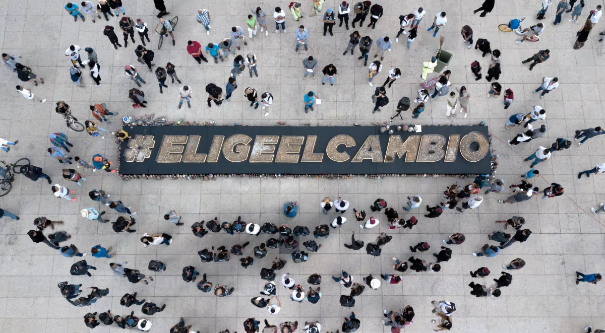 Una multitud rodea las palabras Elige El cambio, que son el mensaje que lanza Philip Morris International invitando a que la gente elija dejar de fumar u optar por productos IQOS, sin humo, que solamente calientan el tabaco