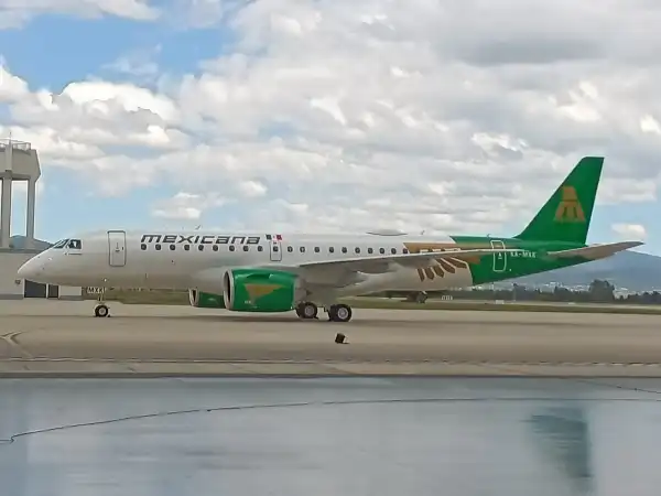 Un avión color blanco con verde y cielo con nubes blancas y cielo azul.jpeg