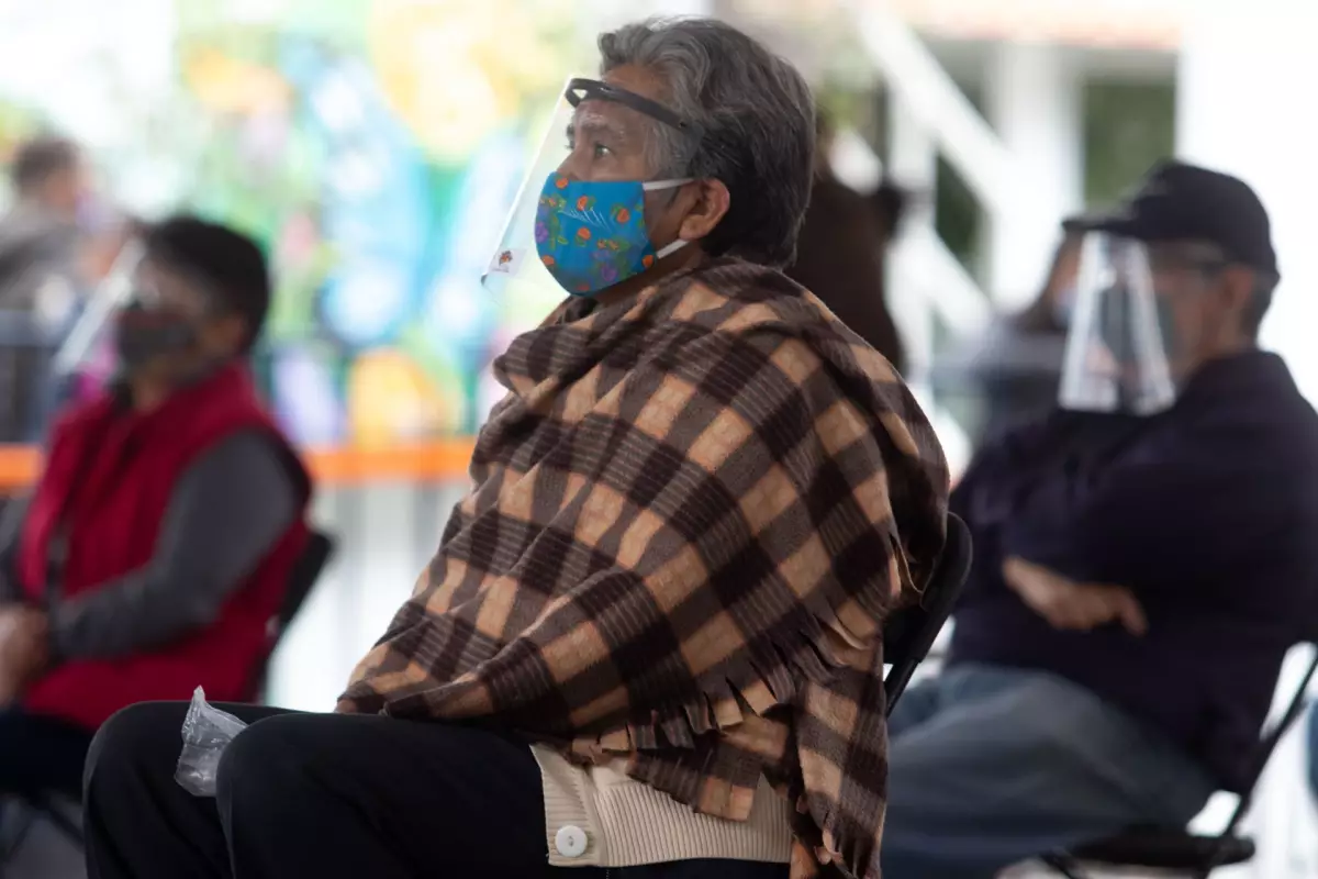 Una señora adulta mayor esperando en una silla.