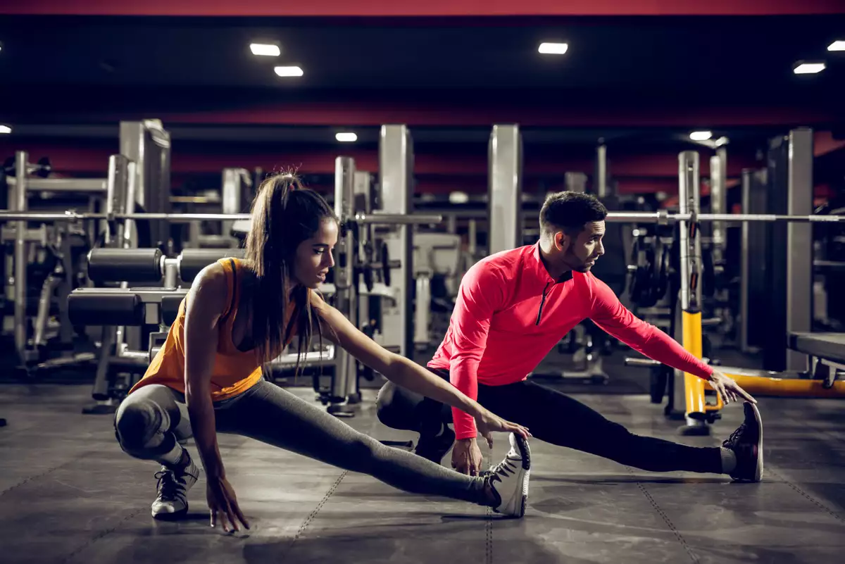 (Mujer entrenado junto con su entrenador en un gimnasio)