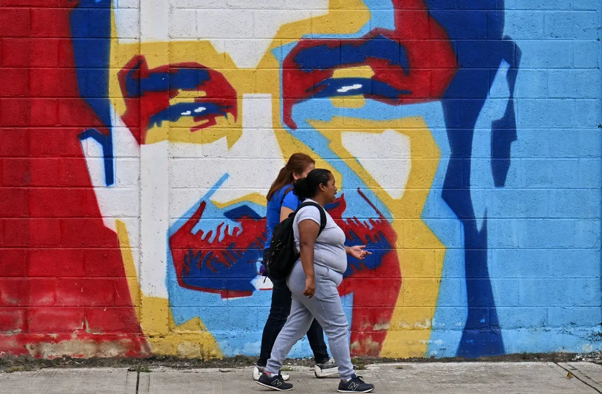 Mujeres caminan frente a un mural del derrocado presidente venezolano Nicolás Maduro en Caracas el 10 de enero de 2026.