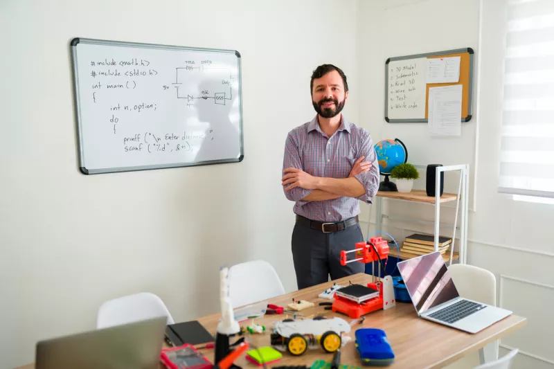 Male teacher looking happy ready for a robotics class
