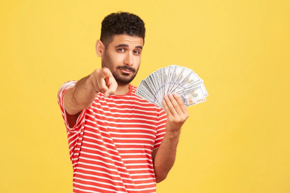 Joven con billetes en la mano. Estas son las metas financieras que debes tener a los 30