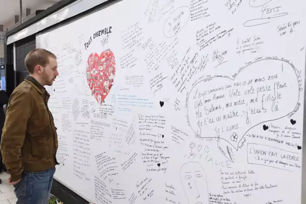 Usuarios del metro de Bruselas leen mensajes en un muro de la estación Maelbeek para recordar a las víctimas de los atentados de marzo pasado.