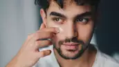 foto de un hombre untándose una crema para eliminar las ojeras alrededor de los ojos