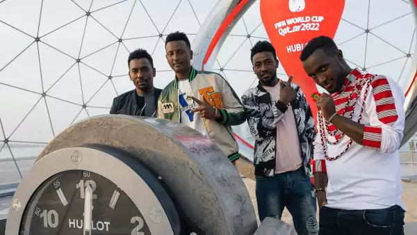 (Migrantes posan en el reloj de la cuenta regresiva para la Copa Mundial, Qatar 2022)