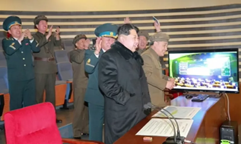 Kim Jong Un (de abrigo negro) recibe la felicitación de sus ministros, tras dirigir el lanzamiento de un satélite este domingo (Foto: AFP Photo/KCNA vía KNS)