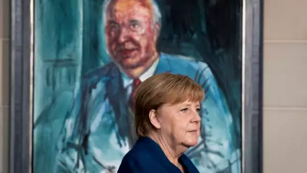 La canciller deAlemania, Angela Merkel, parada frente de un retrato del ex canciller Helmut Kohl. 