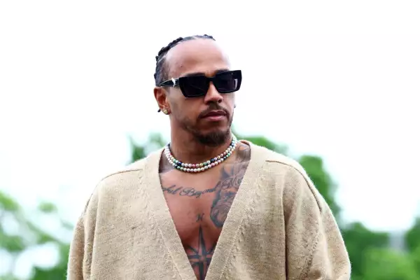 foto del piloto Lewis Hamilton usando dos collares de perlas y un suéter ligero además de lentes oscuros