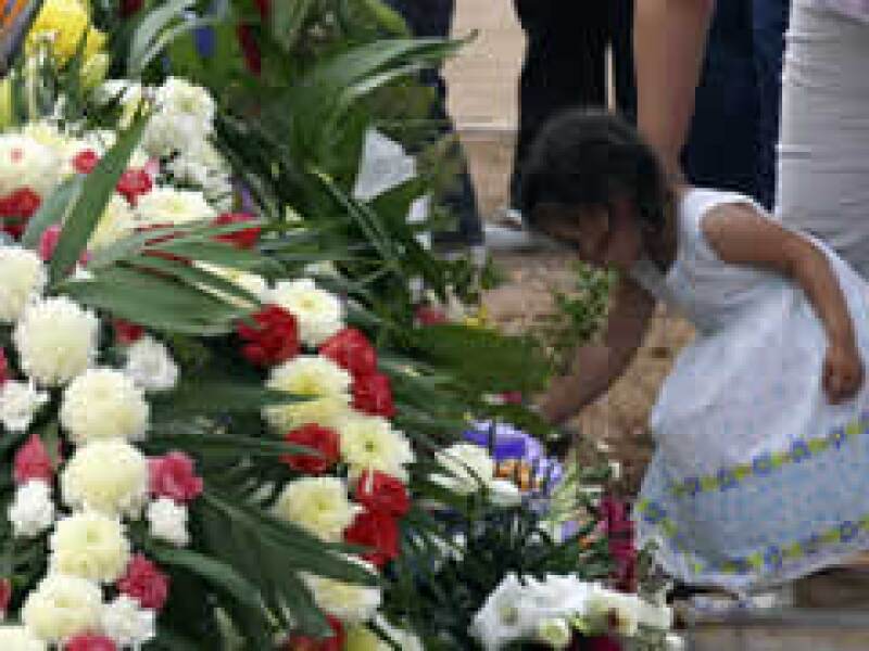 Ua pequeña deposita una flor durante el entierro de las víctimas del incendio. (Foto: Reuters)
