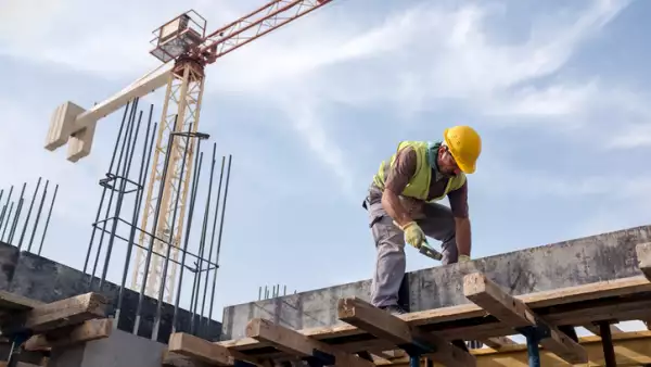 Worker At Construction Site Is Fixing The Form For The Beam