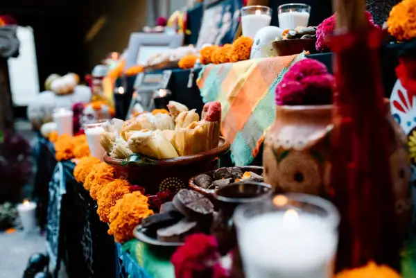Ofrenda de Día de Muertos con velas blancas y comida. 