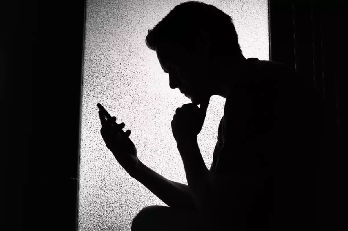 Young man reading on smartphone at home.