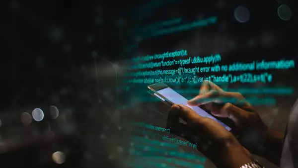 Mujer usa un teléfono con códigos de programación de fondo. 