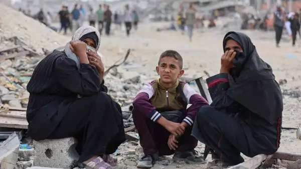 Mujeres palestinas y un niño miran mientras la gente se une para recoger paquetes de alimentos después de que los camiones de ayuda entraran desde el cruce de Karem Abu Salem, en Khan Yunis, en el sur de la Franja de Gaza, el 12 de octubre de 2025, mientras se celebra un alto el fuego entre Israel y las facciones palestinas en el territorio sitiado.