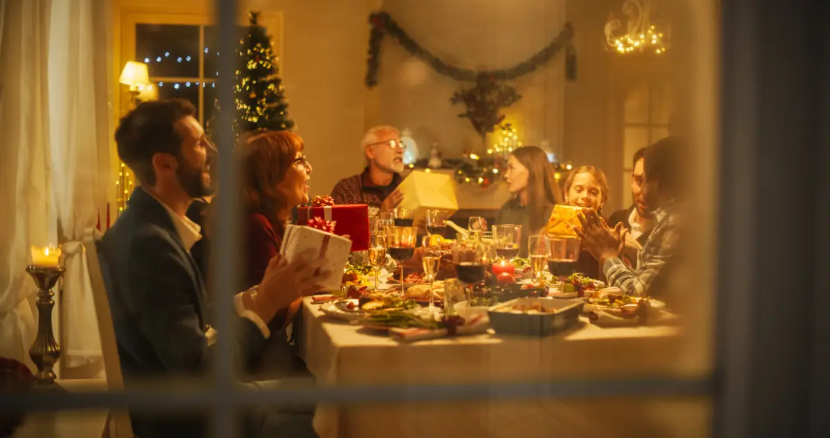 Foto de una familia reunida en una mesa durante la cena de Navidad e intercambiando regalos.