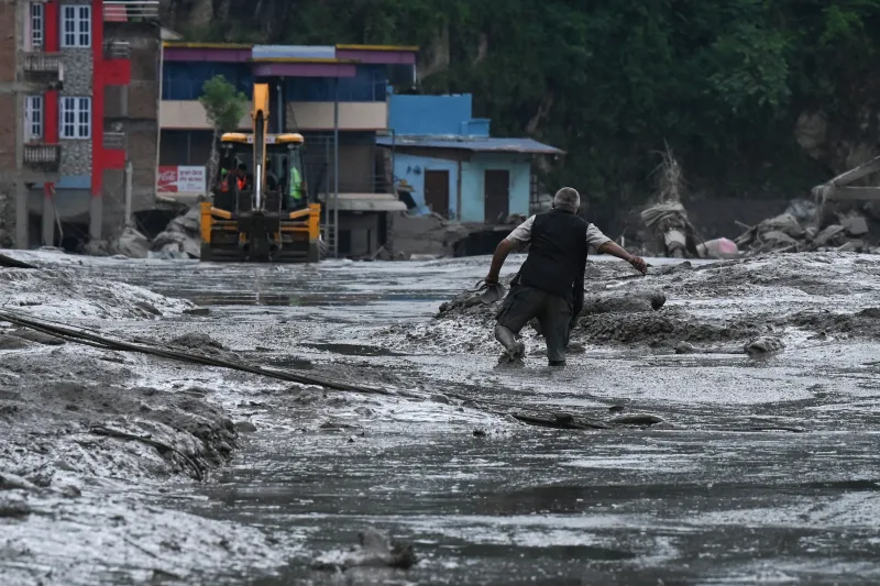 Un residente camina por una calle cubierta de barro tras unas inundaciones repentinas y un deslizamiento de tierra en Devighat, en el distrito nepalí de Nuwakot, el 26 de agosto de 2026. Los equipos de rescate se movilizaron con urgencia el 27 de agosto para localizar a cientos de personas desaparecidas en la frontera entre Nepal y el Tíbet, a causa de inundaciones repentinas y deslizamientos de tierra que causaron la muerte de al menos 160 personas y arrasaron aldeas enteras. 