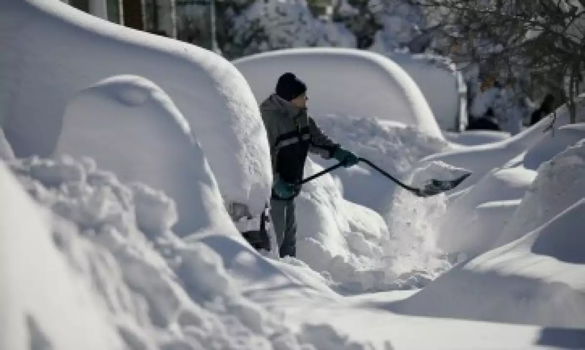 Un residente de Union City retira la nieve de la entrada de su casa, donde quedó sepultado su auto en New Jersey (Foto: Reuters)