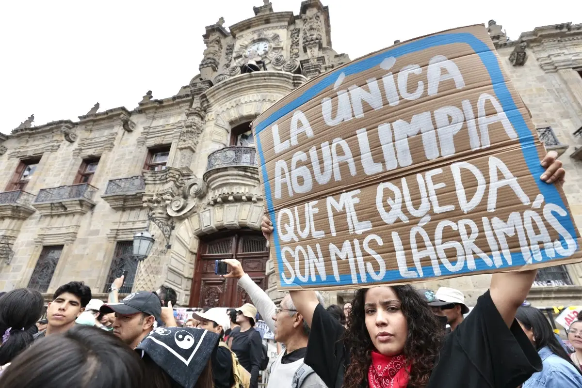 En la imagen, una joven sostiene una pancarta con la frase "La única agua limpia que me queda son mis lágrimas".