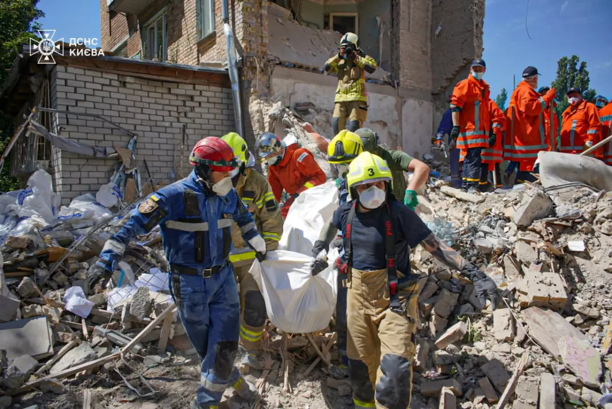 Los rescatistas llevan el cuerpo de una persona encontrada bajo los escombros en el lugar donde un edificio de apartamentos fue alcanzado por un ataque con misiles rusos, en medio del ataque de Rusia a Ucrania, en Kiev, Ucrania, el 9 de julio de 2024.