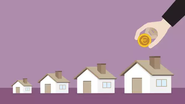 Businessman putting a euro coin into a big house