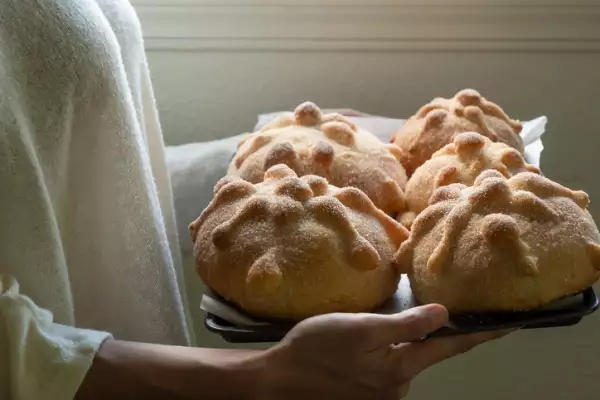 Woman holding tray with traditional Mexican pan de muerto (bread of the dead)