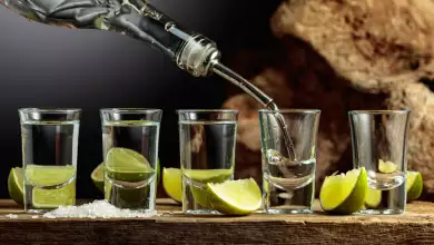 Silver Tequila with salt and lime slices on an old wooden board.
