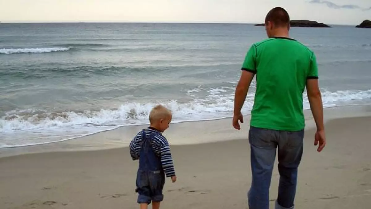Un padres camiona en la playa con su hijo