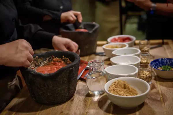 Foto las manos de cocineras moliendo jitomates en molcajetes para preparar sikil paak.