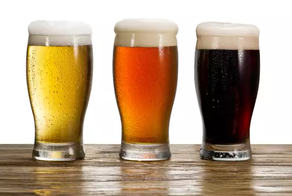 Foto de tres tipos de cerveza servidos en vasos: clara, ámbar y oscura.