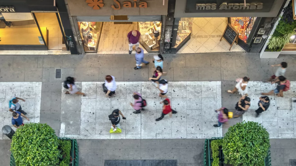 Personas caminando frente a tiendas comerciales.