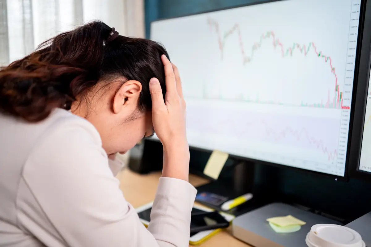 mujer preocupada, de fondo una gráfica financiera