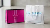 Dos bolsas de compras juntas: del lado izquierdo, una bolsa rosa de Liverpool y del lado derecho está una bolsa de tela de Primark. 