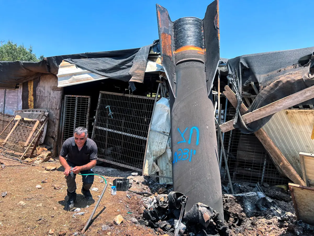 Un hombre posa junto a los restos aparentes de un misil balístico después del ataque de misiles de hoy por parte de Irán contra Israel, en el norte de Israel, el 24 de junio de 2025 (Imagen principal del artículo web "El costo para Israel por mantener múltiples guerras en simultáneo").