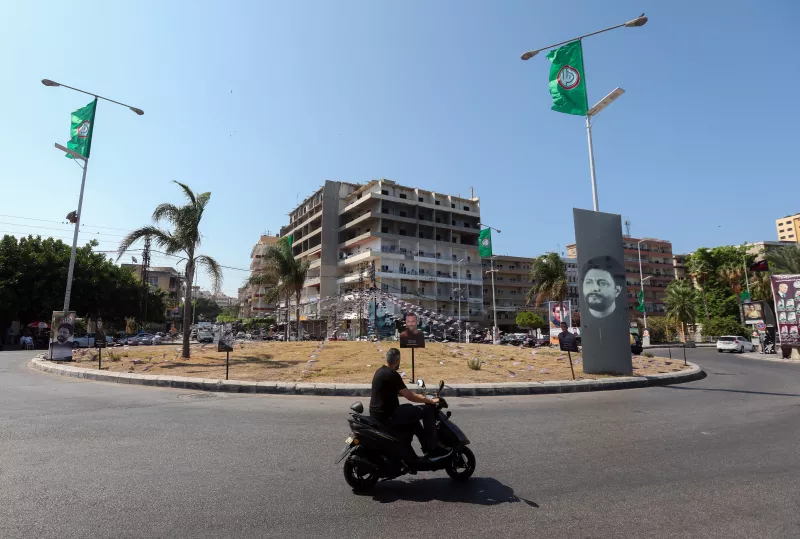 Un hombre monta un ciclomotor en una rotonda decorada con una foto del imán Musa al-Sadr, el fundador del Movimiento Amal chiíta que desapareció después de viajar a Libia en 1978, y la bandera del Movimiento Amal, en Tiro, al sur del Líbano, el 26 de agosto de 2024 (Foto principal del artículo 'Un 'apocalipsis': habitantes de Líbano y de Israel temen que el conflicto se prolongue')