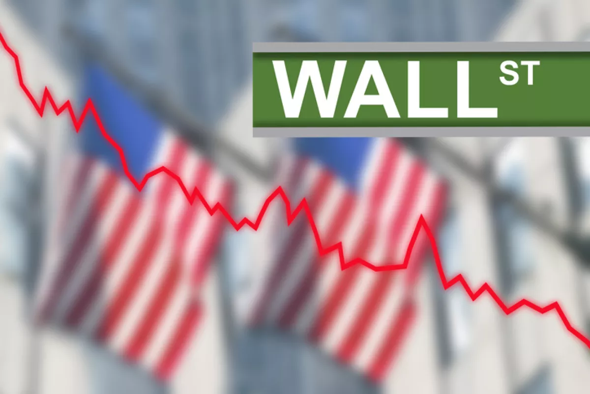 Al fondo, dos banderas difuminadas de EU con una gráfica hacia abajo y la palabra Wall Street en grande.