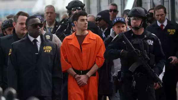 Foto de Luigi Mangione esposado, vistiendo el uniforme anaranjado de prisionero y rodeado de policías poco después de su detención.