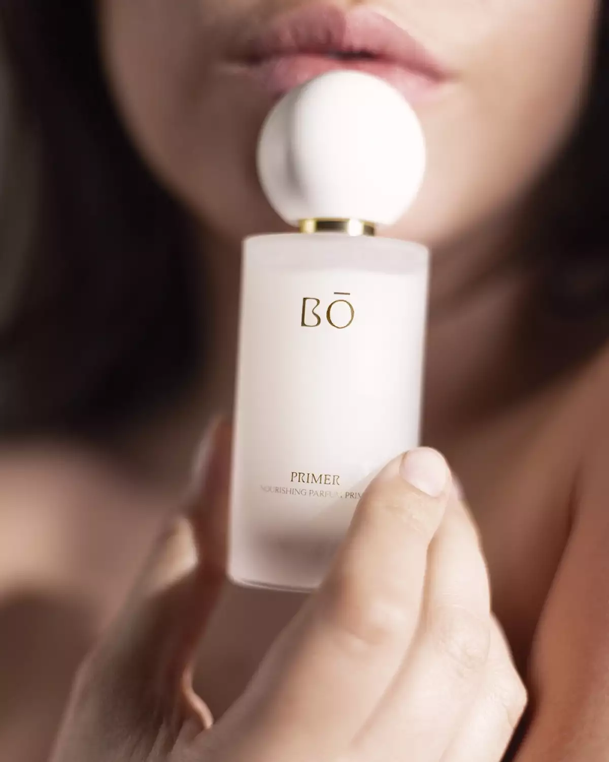 mujer sosteniendo una botella de primer para perfume. 