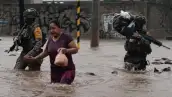 Dos integrantes del ejército ayudan a una mujer en medio de inundaciones.jpg
