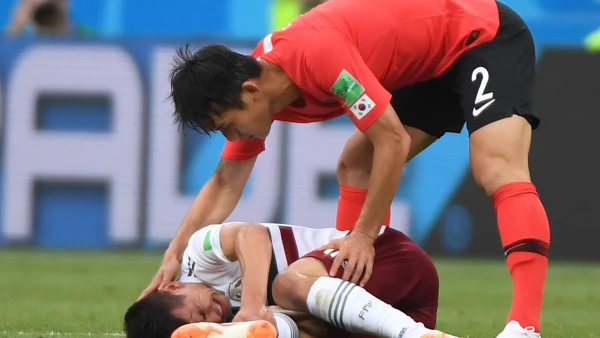 El surcoreano Lee Yong asiste al mexicano Hirving Lozano tras una falta
