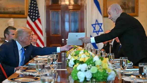 El primer ministro israelí Benjamin Netanyahu (R) entrega una carta al presidente estadounidense Donald Trump mientras se reúnen en la Sala Azul de la Casa Blanca en Washington, DC, el 7 de julio de 2025.