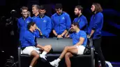 Foto de Rafael Nadal y Roger Federer sentados en una banca despidiéndose uno del otro. Federer se cubre el rostro para limpiarse las lágrimas y Nadal lo ve sonriendo.